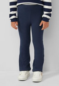 Leggings in cotone blu navy con una vestibilità aderente, caratterizzati da una texture uniforme e un leggero svaso all'orlo, abbinati a sneaker bianche.
