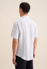 Camicia a maniche corte a righe con linee verticali blu e bianche, colletto tradizionale e orlo curvo. Realizzata in tessuto leggero.