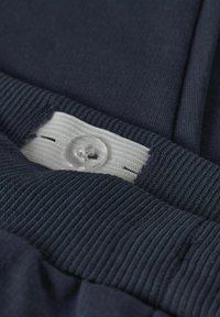 Tissu bleu marine avec texture côtelée, doté d'une ceinture élastique blanche et de détails en plastique transparent.
