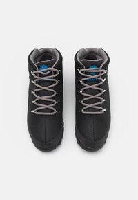 Černé turistické boty s texturovaným povrchem, šedými tkaničkami a výrazným modrým logem na jazyku. Robustní gumová podrážka pro lepší přilnavost.