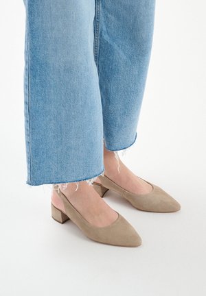 Beige Wildleder-Blockabsatzschuhe mit spitzem Zehen und offenem Absatz, getragen mit hellblauen, cropped Jeans mit fransigen Säumen.