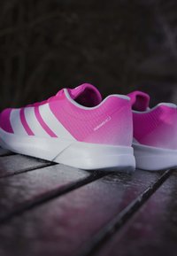 Baskets de sport roses avec un dessus texturé, trois rayures blanches et une semelle blanche avec un léger dégradé. Modèle : Duramo RC2.