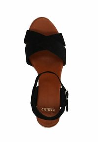 Black suede sandal with crossed straps, tan leather insole, and adjustable ankle strap featuring silver hardware. Flat sole, minimal design.