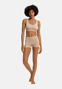 Conjunto de top sin mangas y pantalones cortos en color beige, fabricado con un tejido suave y elástico que tiene una textura lisa y sin costuras visibles.