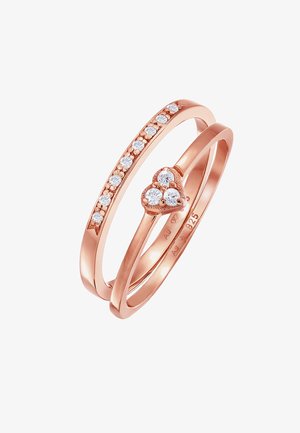 Ringe aus Roségold mit einem glatten Band und einem Cluster aus klaren Steinen in Herzform, der in der Mitte eines Bandes gesetzt ist.