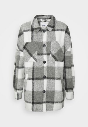 Veste en laine à carreaux gris et blanc, boutonnée, avec col, manches longues et poches plaquées sur la poitrine, sur un fond uni.