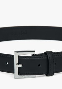 Zwarte lederen riem met een zilveren metalen gesp, voorzien van een logo-engraving, een gladde textuur en meerdere gaatjes voor verstelbaarheid langs de band.