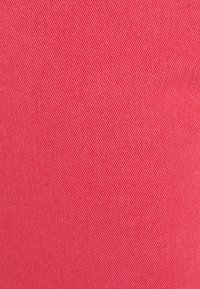 Textil en rosa brillante con una textura suave y un patrón acanalado diagonal, que presenta una apariencia uniforme y consistente. No hay detalles adicionales presentes.