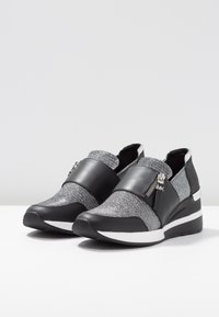 Sneakers neri e silver con una tomaia in tessuto texturizzato, dal design slanciato, con zip decorativa e suola in gomma, dotate di un tacco a cuneo.