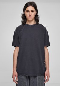 Tricou larg, de culoare neagră, fabricat din bumbac. Dispune de un guler rotund, mâneci scurte și detalii de cusătură vizibile. Textură moale. Croi casual.