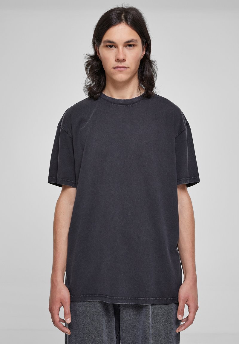 Tricou larg, de culoare neagră, fabricat din bumbac. Dispune de un guler rotund, mâneci scurte și detalii de cusătură vizibile. Textură moale. Croi casual.