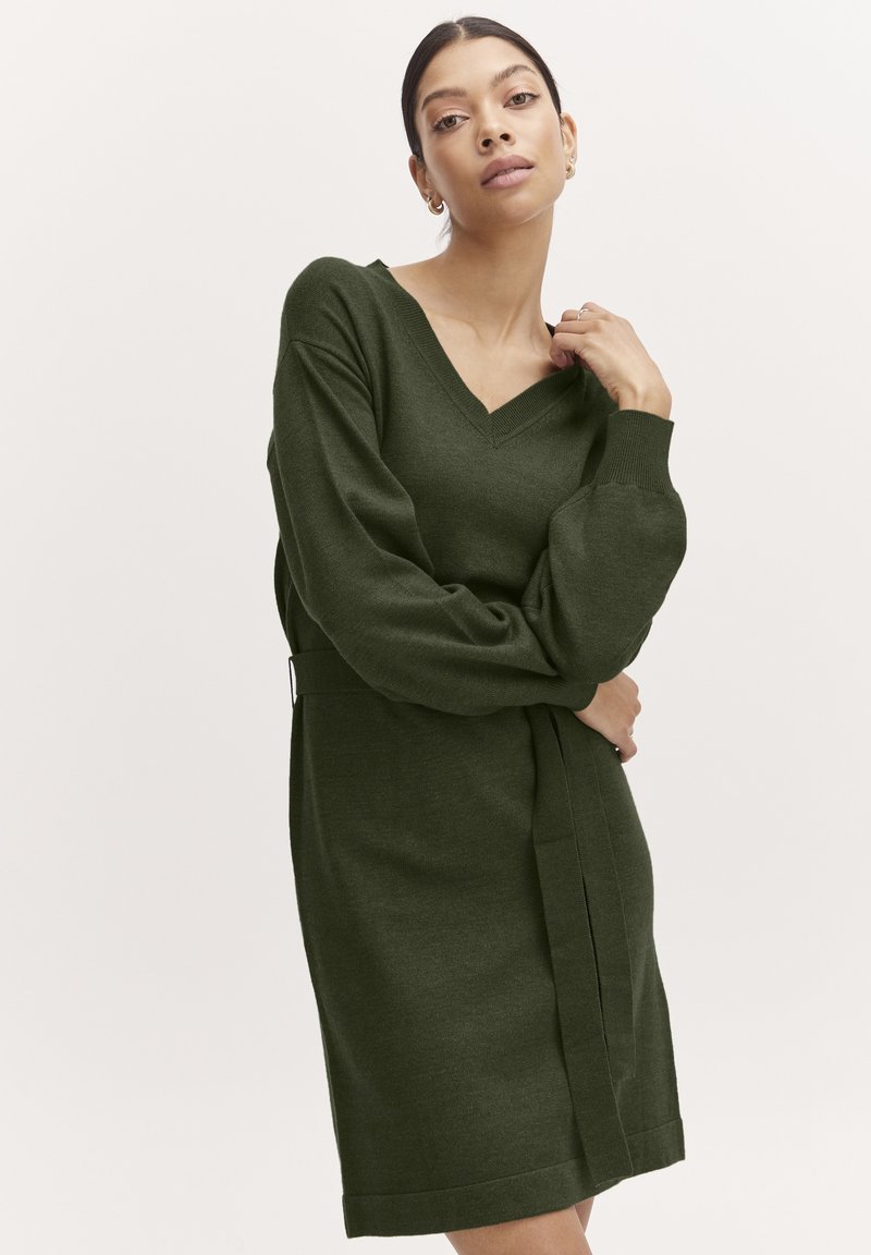 Abito a maglia verde oliva con scollatura a V, maniche lunghe a palloncino e vita con cintura. Texture morbida e design al ginocchio.
