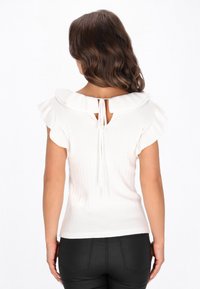 White ribbed top with short ruffled sleeves and a tie closure at the back. Fitted design, showcasing a smooth texture and elegant neckline.