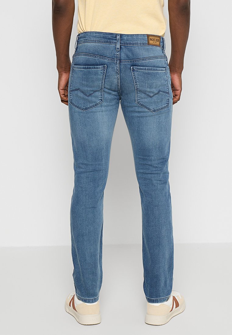 Niebieskie dżinsy o slim fit, z dwoma tylnymi kieszeniami w wzór chevron, średniej barwy, z metką skórzaną z logo na pasku.