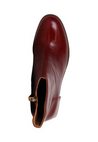 Botín de tobillo de cuero rojo con textura suave, punta afilada y cremallera lateral con un acento dorado. Suela plana marrón.