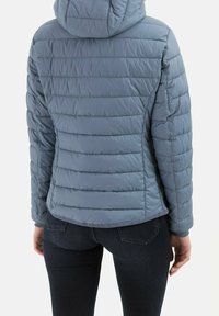 Lyseblå dunjakke med en tætsiddende silhuet, lodrette sømme og hætte. Har en glat tekstur og en cropped rygkant.