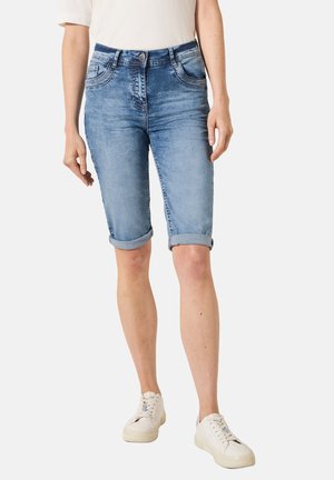 Bermudas en denim bleu clair avec ourlets roulés, cinq poches et décoloration subtile. Dispose d'une taille classique et d'une fermeture à bouton métallique.