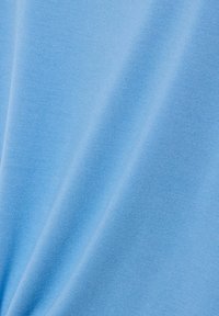 Gładka jasnoniebieska tkanina o delikatnej, drobnej strukturze dzianiny, z łagodnymi fałdami tworzącymi miękkie cienie i refleksy.