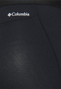 Crni aktivni materijal s glatkom teksturom, s kontrastnim šavovima i bijelim Columbia logotipom blizu struka.
