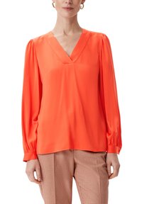 Helles orange Bluse aus glattem Stoff, mit V-Ausschnitt, langen Puffärmeln und lässiger Passform, kombiniert mit karierten Hosen.