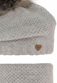 Cappello lavorato a maglia grigio con superficie strutturata, sormontato da un pon pon di pelliccia e caratterizzato da un'etichetta marrone a forma di cuore con la scritta "LOVE" in rilievo.
