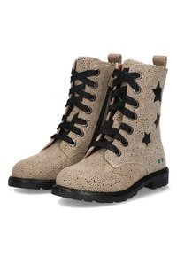 Beige enkelbottinen van geperforeerd materiaal, met zwarte steraccenten, zwarte veters en een gestructureerde zool. Ritssluiting aan de zijkant voor gemakkelijke instap.