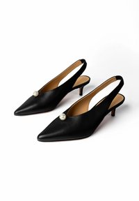 Fekete hegyes slingback magassarkú alacsony tűsarkúval, nagy fehér gyönggyel díszítve a tetején, barna belső béléssel, fehér háttéren.