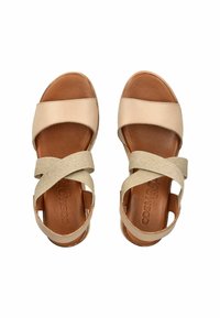 Beige Leder-Sandalen mit kreuzverlaufenden Stoffriemen. Sie verfügen über eine bequeme braune Innensohle und ein rundes Zehendesign.