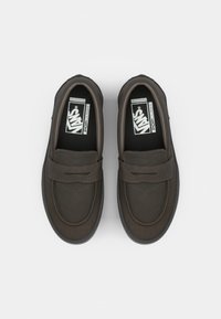 Mørkebrune slip-on sko med en glatt, læraktig tekstur, som har et sydd design og en polstret krage. Svarte innersåler med logo.