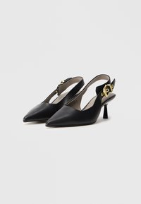 Mustat nahkaiset slingback-kengät, joissa on terävät varpaat ja pieni, kiiltävä korko. Kultaista metallia koristeina strapsseissa. Tasainen pinta.