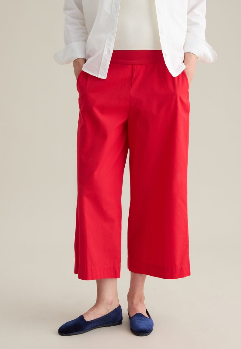 Rode cropped broeken met een elastische tailleband, gemaakt van lichtgewicht stof. Draagt met marineblauwe ballerina's.