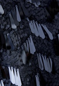 Schwarzer Stoff mit übereinander liegenden, kreisförmigen Pailletten und elongated metallischen Etiketten, die eine strukturierte, schimmernde Oberfläche mit kontrastierenden Farbtönen schaffen.