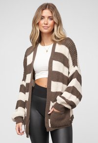 Brun- og kremstripet strikket cardigan med store ermer, �åpen front og lommer. Ribbet tekstur, mykt materiale og avslappet passform.