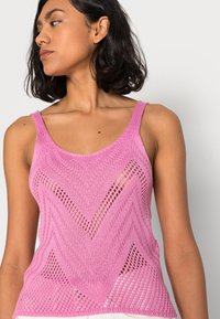 Top a canottiera lavorato a maglia rosa con motivo a zigzag, intreccio aperto e spalline regolabili, dall'aspetto leggero e testurizzato.