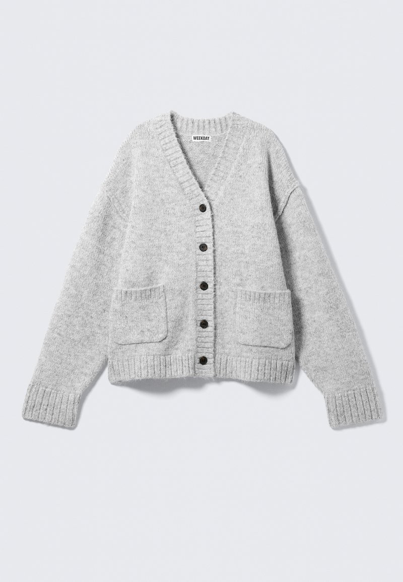 Grå strikket cardigan med V-hals, ribstrikkede ærmekanter og to forlommer. Har seks sorte knapper langs midten. Blød tekstur.