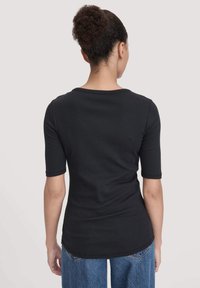 Zwart aansluitend T-shirt met korte mouwen, ronde halslijn en een gladde textuur, gecombineerd met losse blauwe denim jeans.