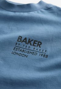 Zila kokvilnas T-kreklu ar melnu izdrukātu logos: "BAKER BY TED BAKER ESTABLISHED 1988 LONDON", ar gludu tekstūru un apkakli ar apaļu izgriezumu.