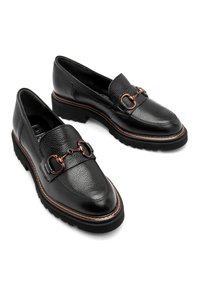 Czarne skórzane mokasyny z teksturowanym wykończeniem, akcenty w kolorze miedzi, gruba czarna gumowa podeszwa oraz kontrastujące brązowe przeszycie.