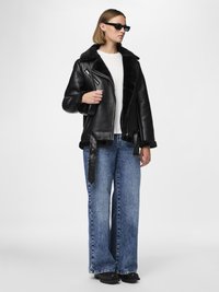 Black leather jacket with a faux fur collar, paired with wide-leg blue denim jeans. Accessories include small black sunglasses.