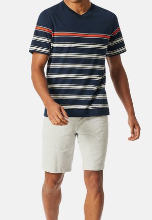 Marineblauwe V-hals T-shirt met horizontale strepen in rood, roomwit en marineblauw, gecombineerd met lichtgrijze short. De stof lijkt zacht en casual.