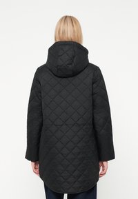 Czarna pikowana kurtka z kapturem, z diamentowym wzorem, o średniej długości i długich rękawach. Gładka tekstura i ograniczone elementy metalowe.