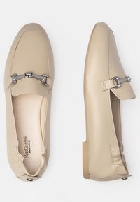 Mocassins en cuir beige avec des accents en métal argenté, bout arrondi, conception à enfiler et couture texturée. Semelle plate et intérieur lisse.