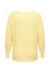 Geltona megzta megzta su trijų ketvirčių rankovėmis, plačiu iškirpimu ir apvalia apačia. Pagaminta iš minkštos medžiagos su tekstūruotu paviršiumi.