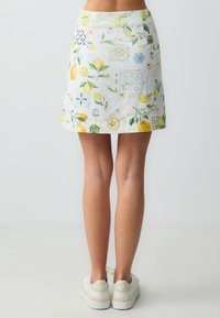 Gonna bianca con motivi di limoni e fiori, caratterizzata da un design aderente e un orlo dritto. Il materiale appare leggero e strutturato.