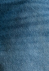 Denim-kangas tummansinisissä sävyissä, joissa on hienovarainen rakenne ja vino kudonta, ja joissa on pieniä värinvaihteluita.