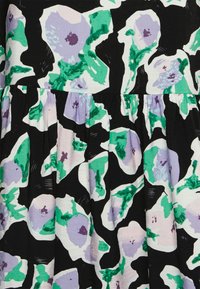 Vestido floral com fundo preto, apresentando grandes flores em lavanda e verde. O tecido é suave, com uma cintura franzida para proporcionar volume.