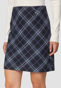 Niebieska spódnica w kratkę mini z jasnoniebieskimi i zielonymi ukośnymi paskami. Wykonana z teksturowanej tkaniny o dopasowanej sylwetce.