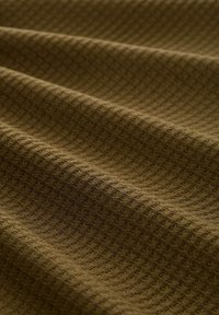 Material textil maro cu un model în diamante, având un aspect moale, țesut. Materialul are o finisare nervurată care îi îmbunătățește calitatea tactilă.