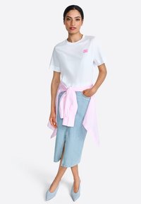White t-shirt with "CIAO" in pink, paired with a light blue denim midi skirt featuring a front slit, and a pink shirt tied at the waist.