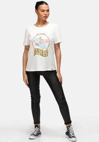 Hvid bomulds-T-shirt med grafisk tryk af Dumbo, kortærmet og afslappet pasform. Sammen med sorte tætsiddende bukser og lærreds sneakers.